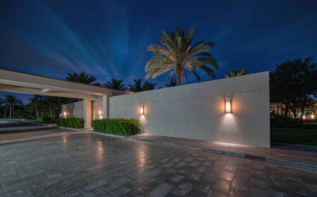 Architectural rendering of wall-mounted outdoor lights washing a villa compound wall at blue hour
